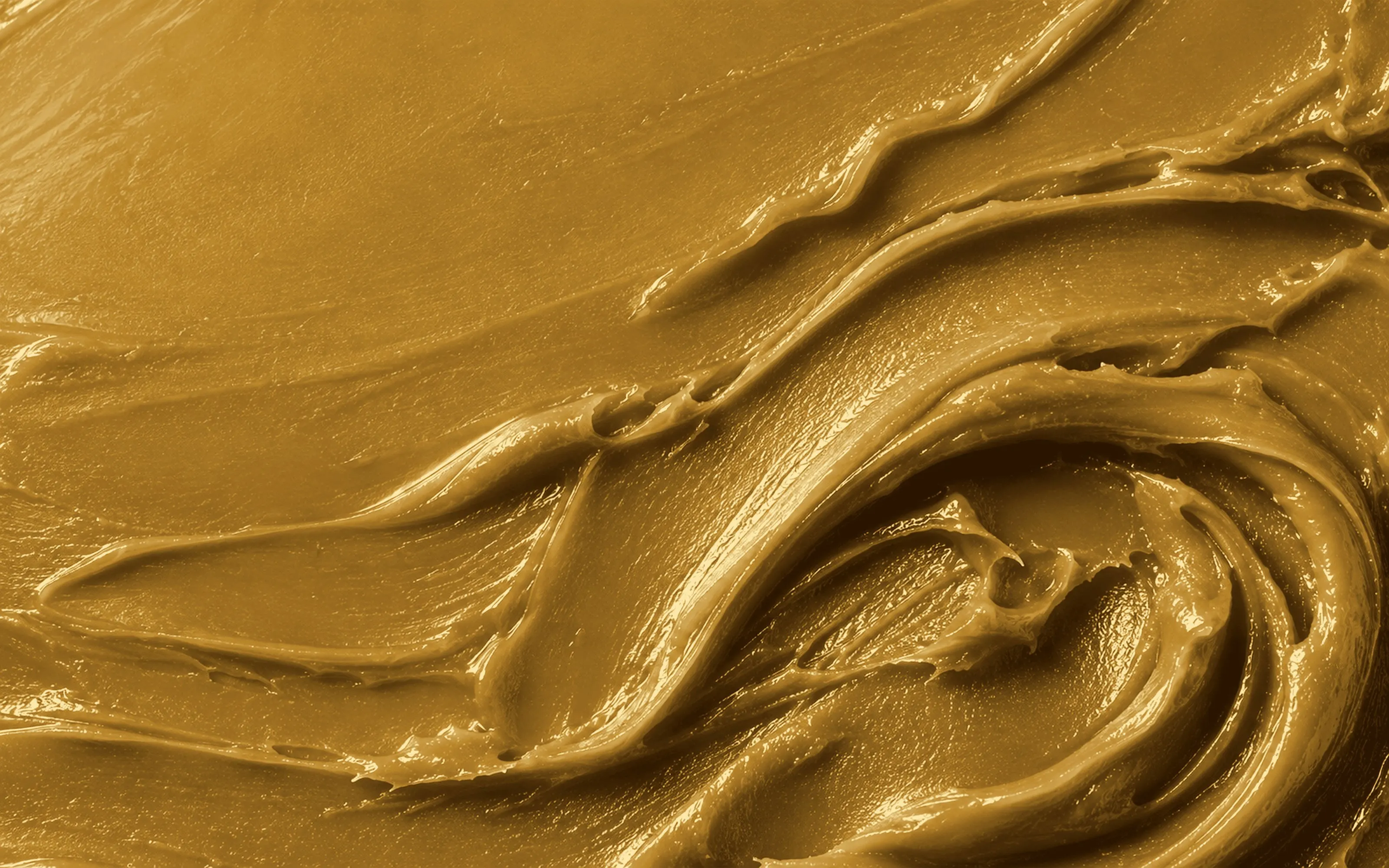 Illustration: cremig verstrichener, glänzender goldfarbener Lipbalm als Textur